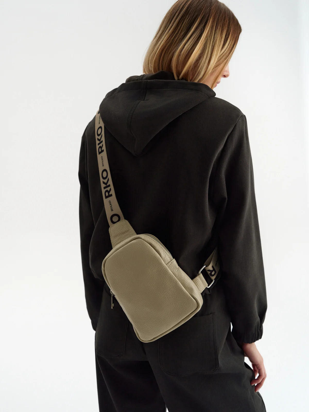 Beżowa torebka typu nerka z ozdobnym paskiem z taśmy