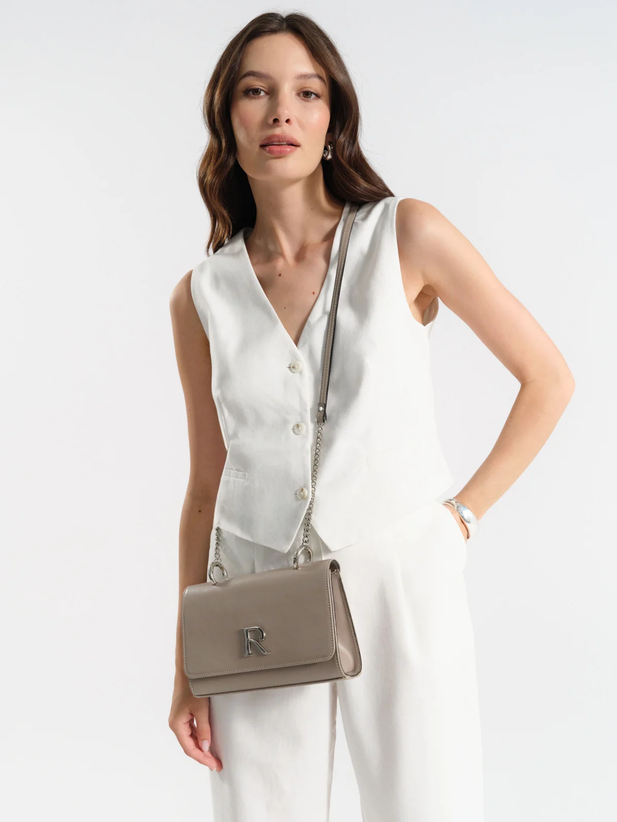 Beżowa torebka typu kopertówka na srebrnym łańcuszku