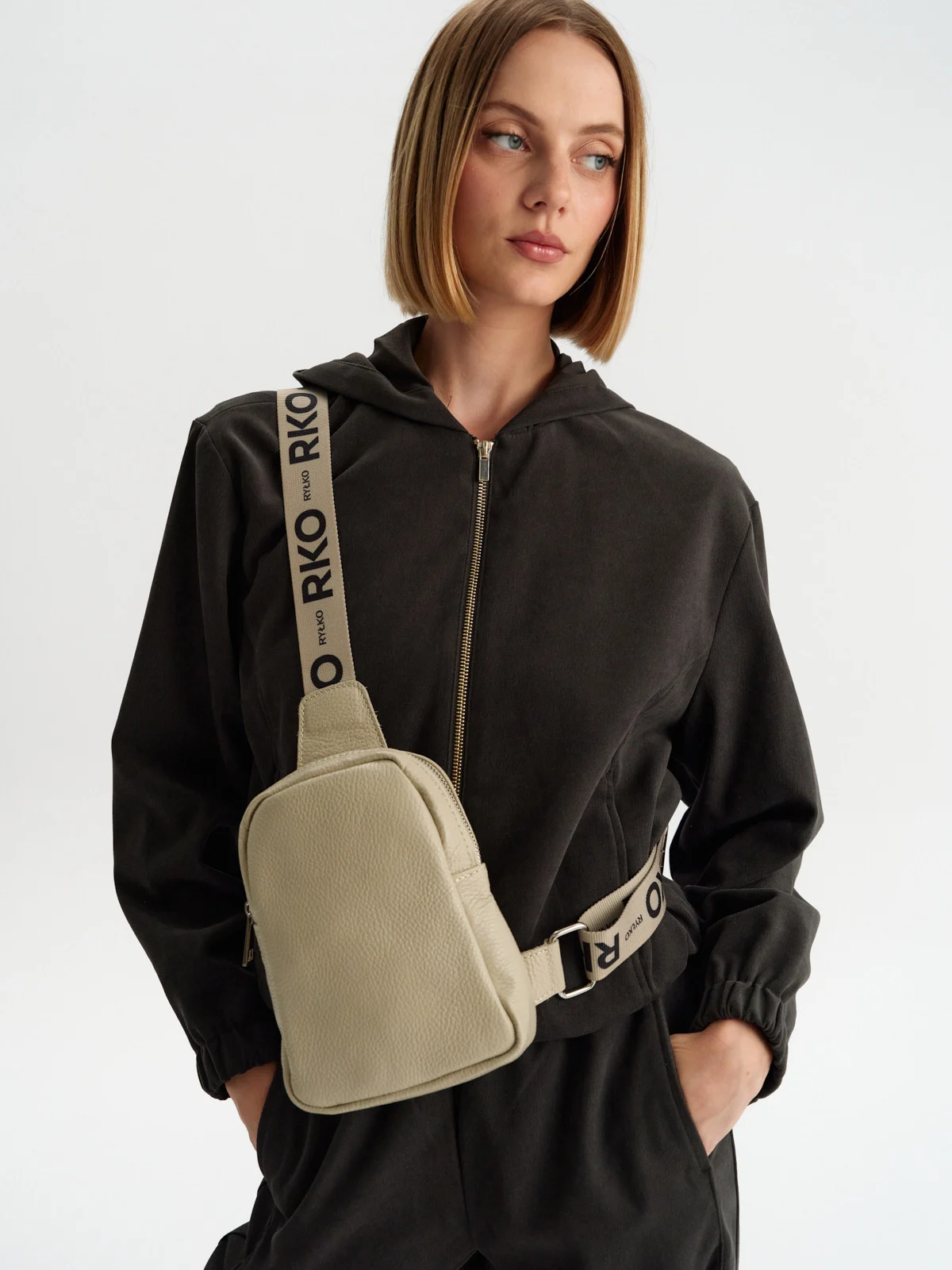 Beżowa torebka typu nerka z ozdobnym paskiem z taśmy