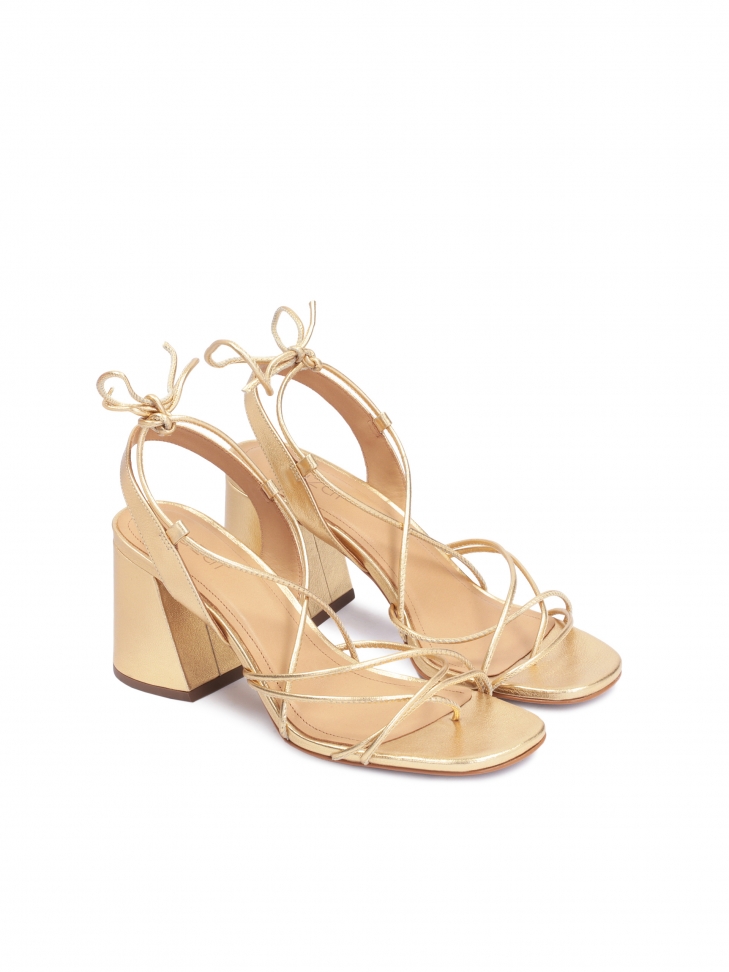 Złote sandały na słupku wiązane wokół łydki