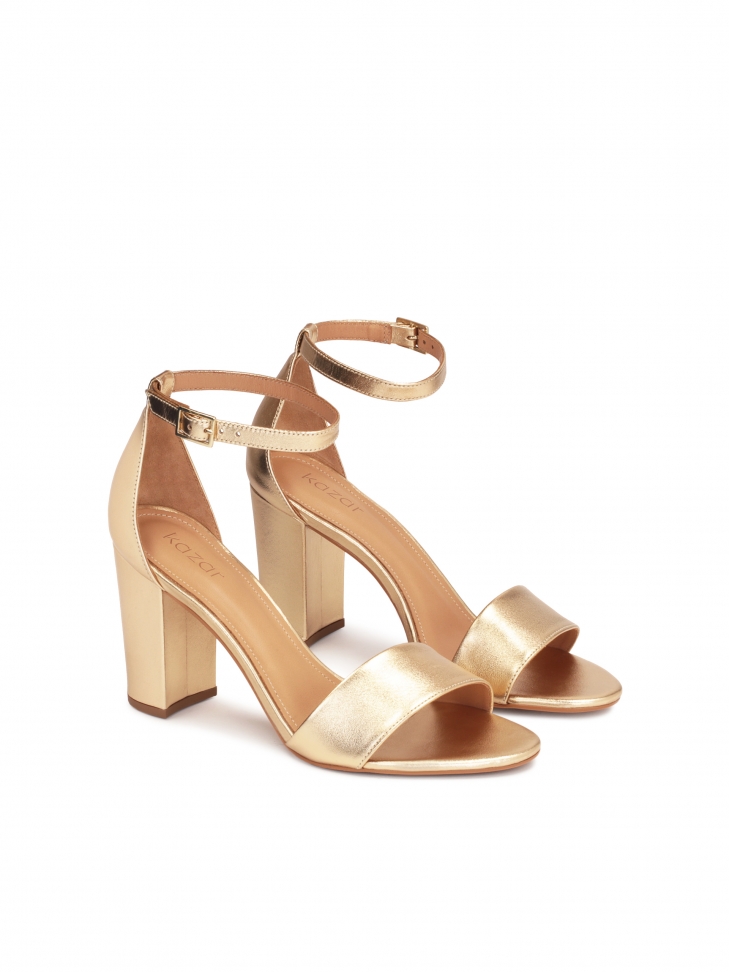 Złote sandały na słupku z paskiem wokół kostki