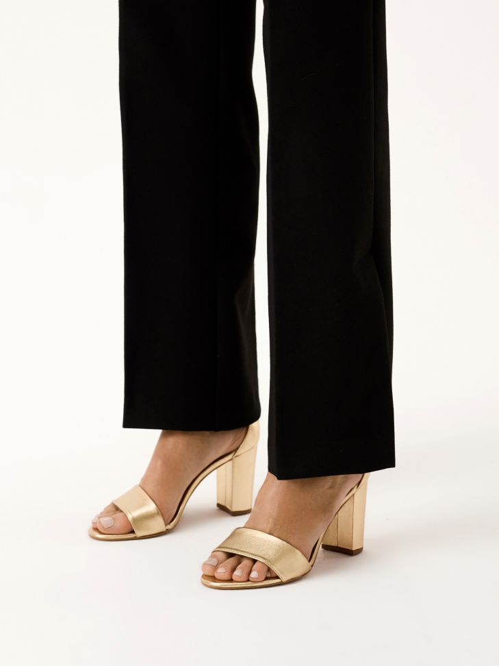 Złote sandały na słupku z paskiem wokół kostki