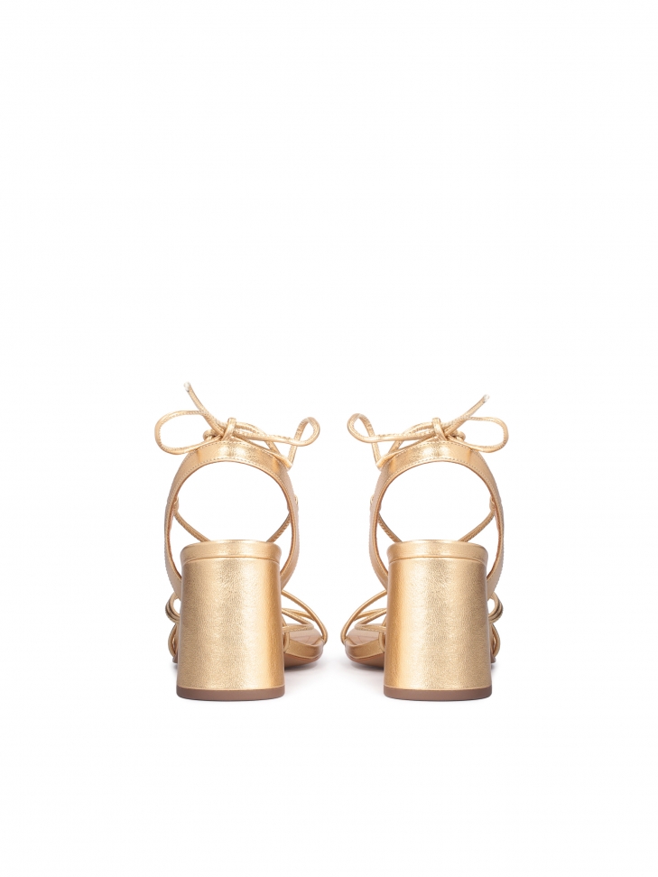Złote sandały na słupku wiązane wokół łydki