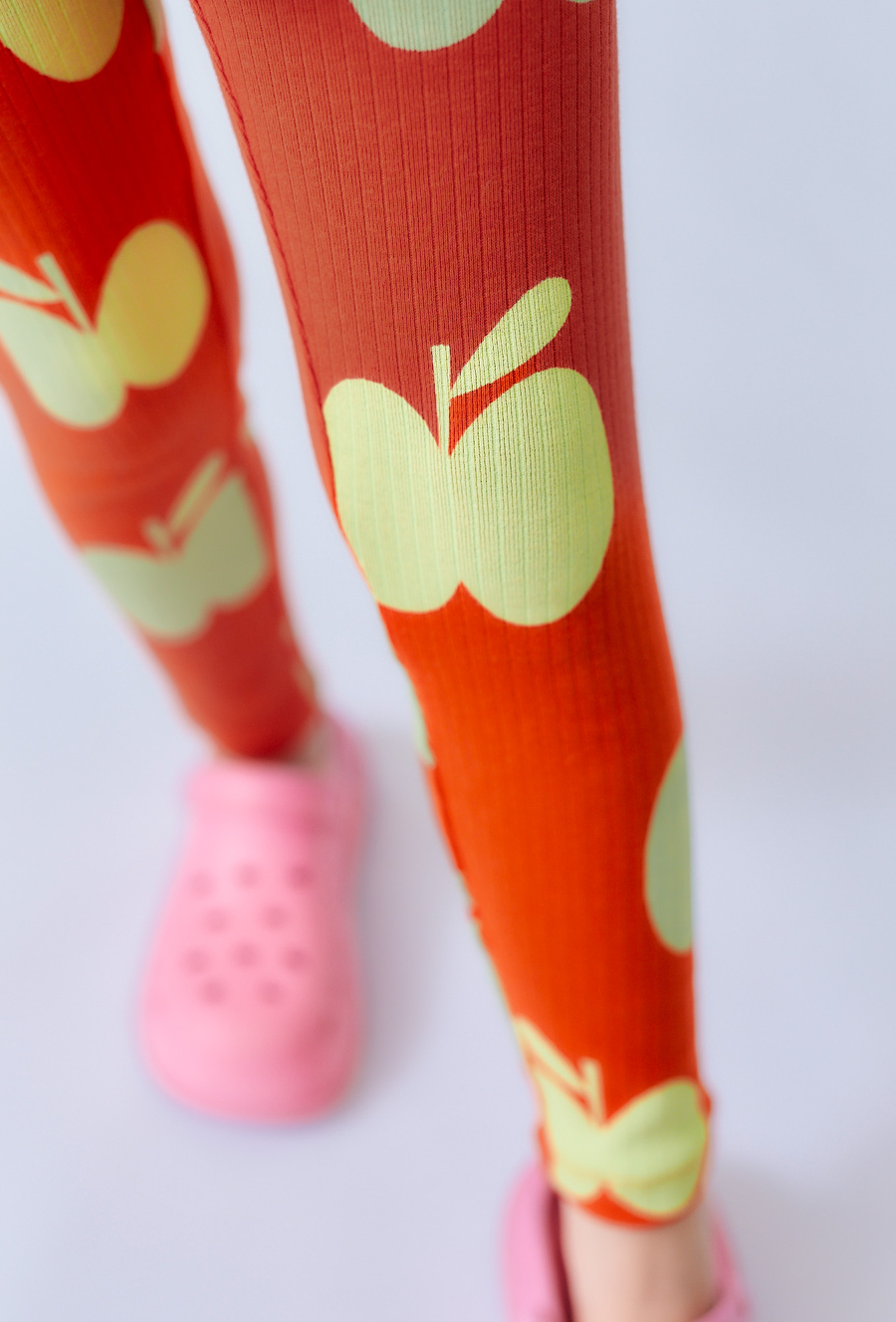 Pomarańczowe legginsy dla dziewczynki z motywem jabłek.