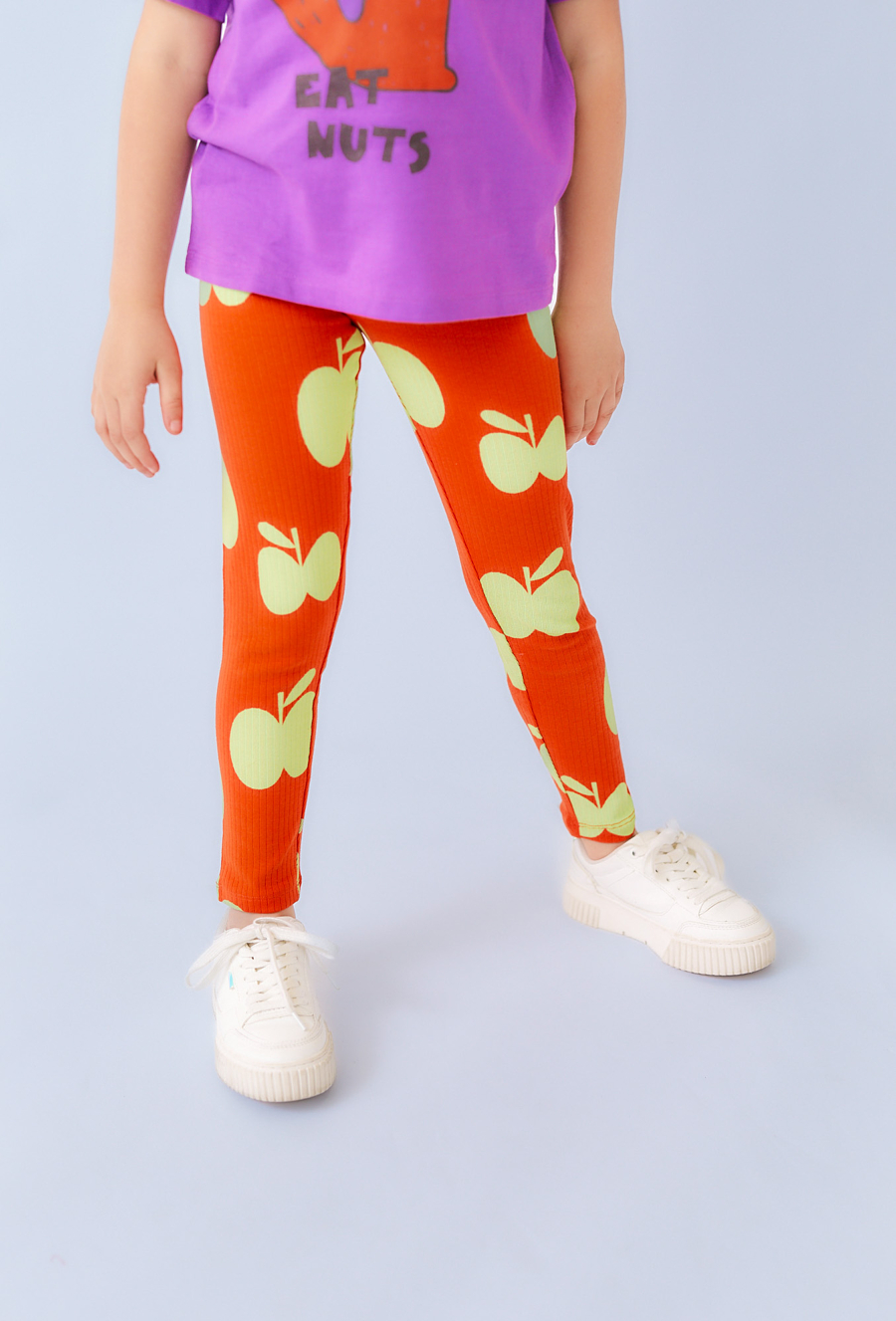 Pomarańczowe legginsy dla dziewczynki z motywem jabłek.