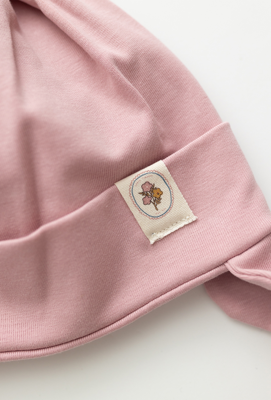 Różowa czapka niemowlęca z wiązaniem i naszywką.