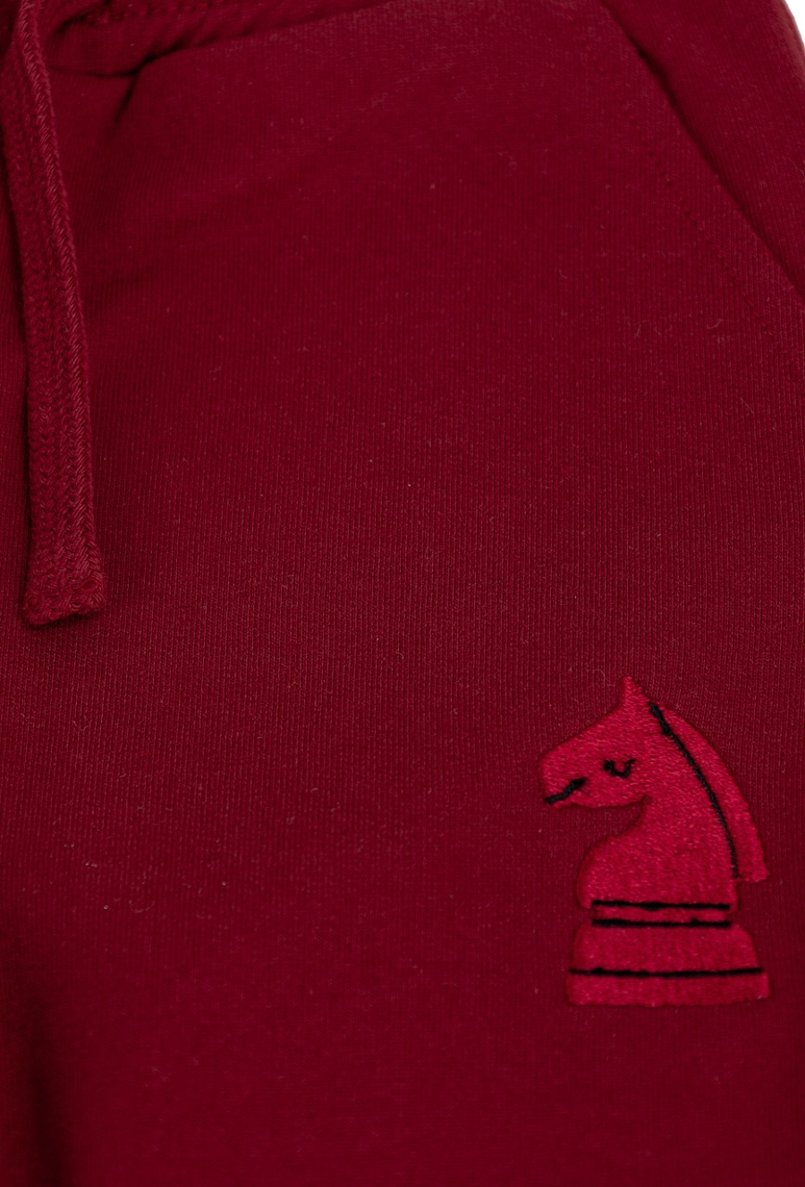 Czerwone spodnie dresowe dziecięce z haftem szachowym.