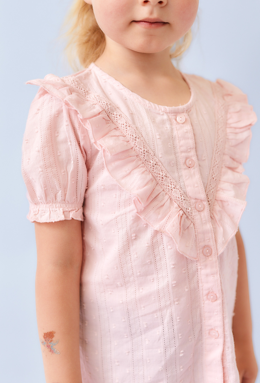 Różowa koszula dziewczęca z ótkim rękawem i falbanką.